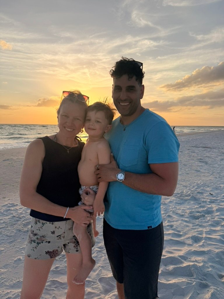 Daniel with his wife and son on the beach at sunset